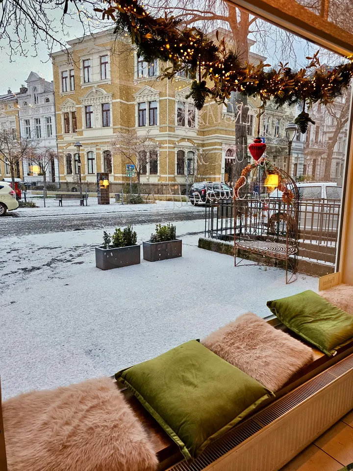 Gemütlicher Fensterplatz mit grünen Kissen und Blick in die verschneite Bonner Südstadt