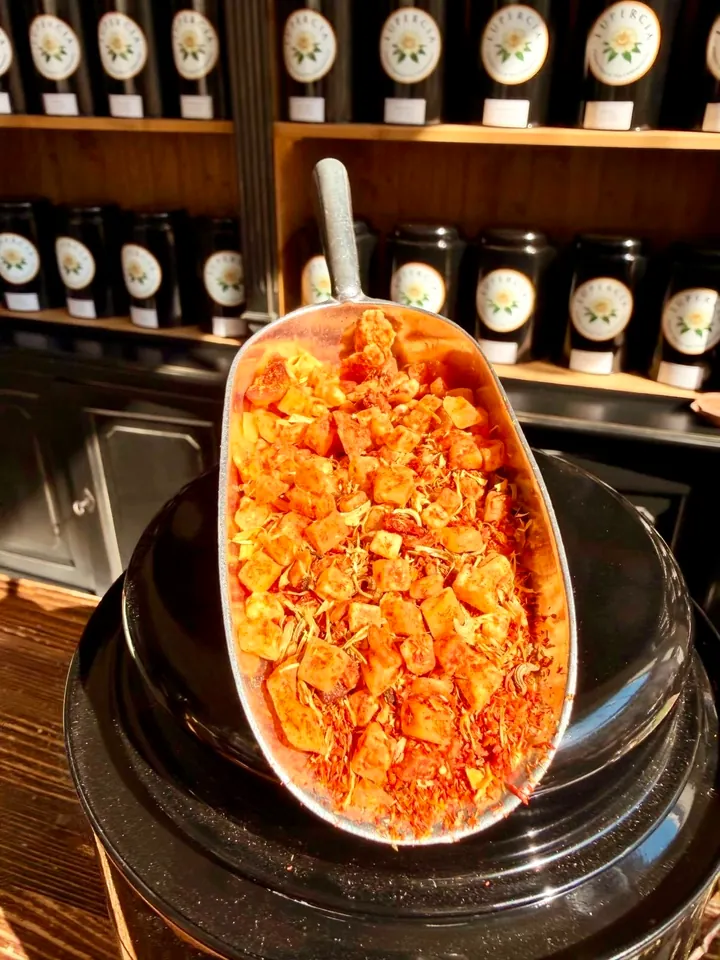 Eine silberne Teeschaufel mit einer leuchtend orangefarbenen Früchteteemischung
