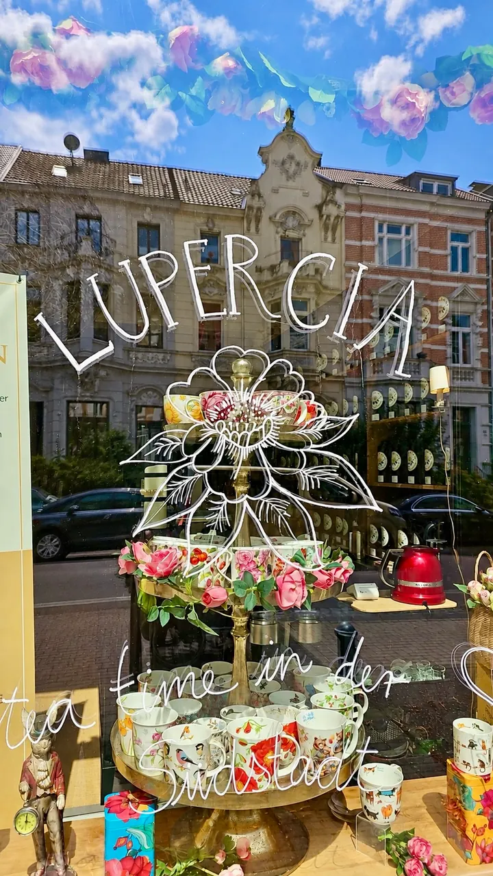 Lupercias Schaufenster mit floralem Logo und gespiegelten Häusern der Bonner Südstadt
