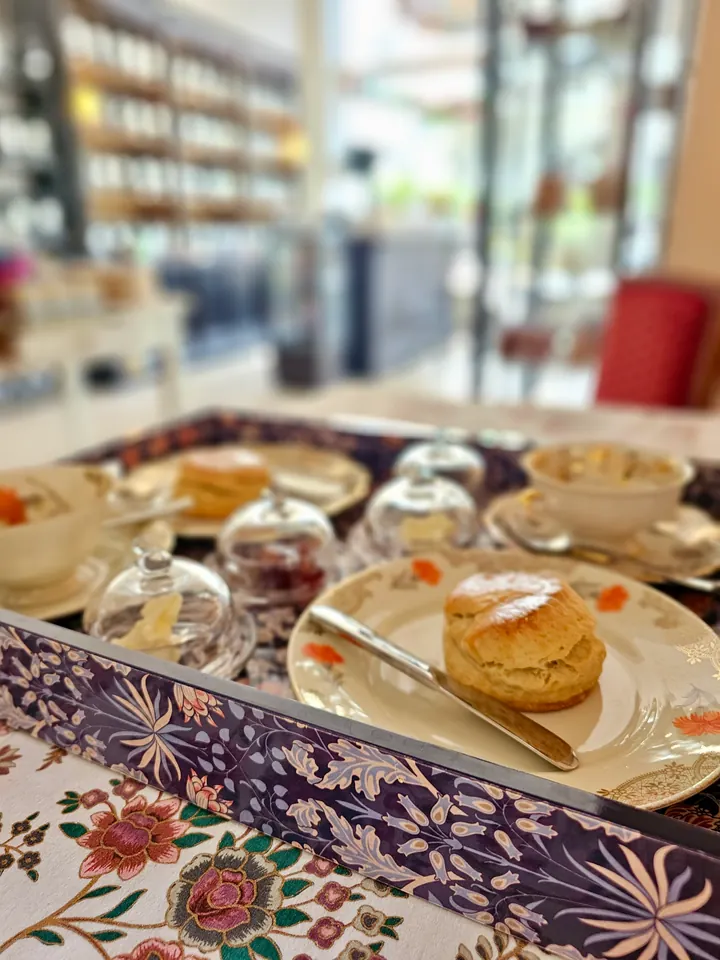 Scones, Konfitüre und Creme auf einem gedeckten Tablett mit floralem Porzellan