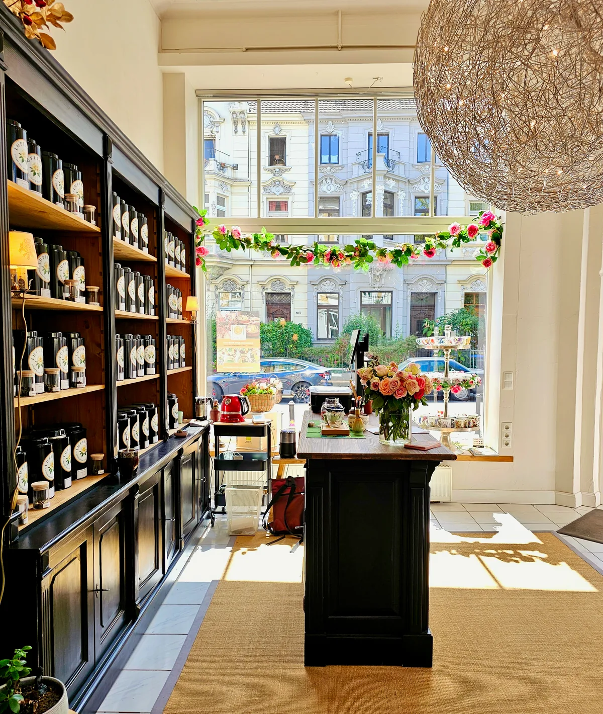 Der lichtdurchflutete Lupercia Salon mit dunklem Teeregal, Blumen und großem Fenster zur Bonner Südstadt
