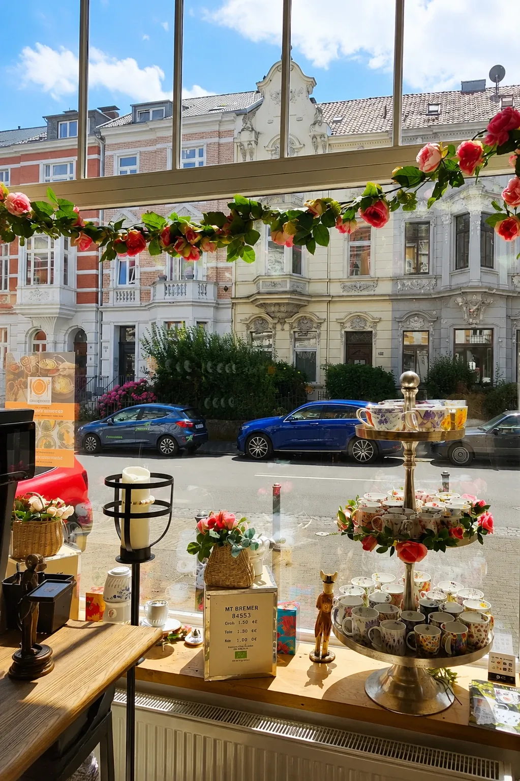 Florale Teetassen und eine Rosengirlande im Lupercia Schaufenster vor den historischen Häusern der Bonner Südstadt