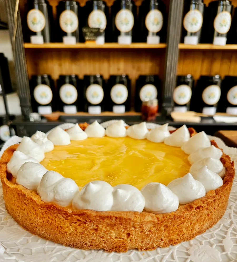 Eine goldgelbe Tarte mit weißer Tupfendekoration vor dem Teeregal von Lupercia