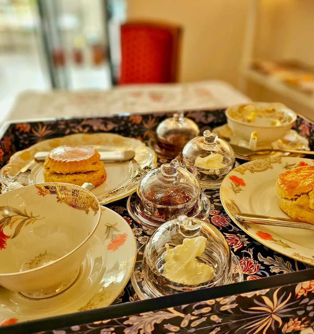 Ein gedecktes Tablett mit Scones, Clotted Cream, Konfitüre und feinem floralen Porzellan