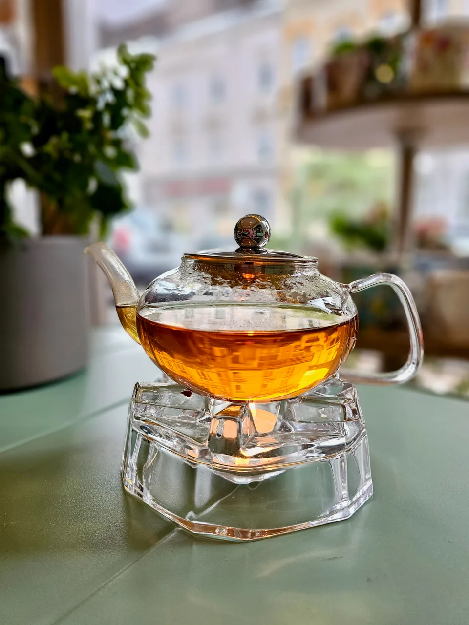 Goldfarben leuchtender Tee in einer Glaskanne auf einem gläsernen Stövchen